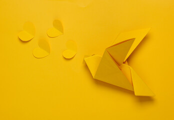 Origami yellow dove with hearts on yellow background. Peace, love concept