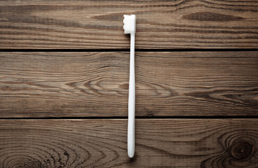 White toothbrush on a wooden table. Top view