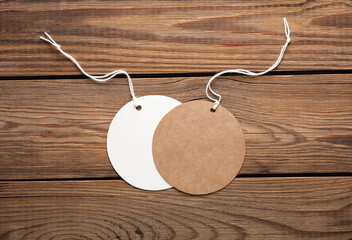 Empty round craft and white paper price tags with string on wooden background. Template for design