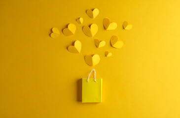 Miniature shopping bag with hearts on a yellow background. Sale, love, shopping concept. Creative...