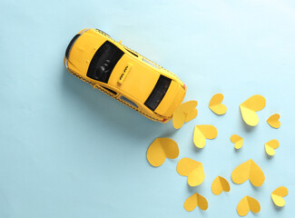 Miniature taxi car with yellow hearts on a blue background. Top view