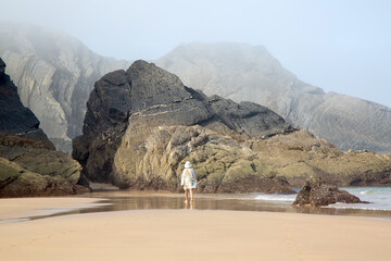 Female Figure with Sea, Cliffs and Rocks With Mist at Odeceixe Beach; Algarve; Portugal