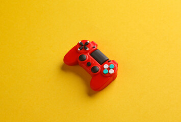 Red toy miniature gamepad on yellow background. © splitov27