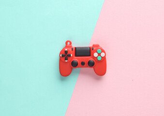 Obraz premium Red toy miniature gamepad on a pink blue background. Top view