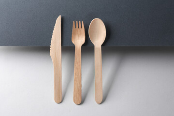 wooden fork, spoon and knife on black and gray background. Creative layout. Minimalism composition. Eco concept