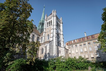 Obraz premium St Pierre Cathedral with lush green vegetation on blue sky background in Geneva, Switzerland