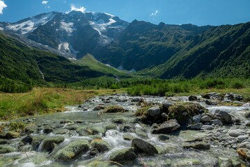 A river streaming in a middle of a green landscape in the Tour Du Mount Blanc