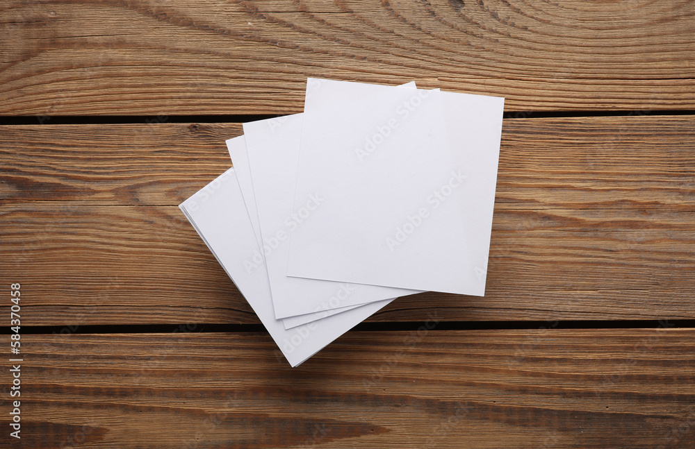 Poster white empty square memo pieces of paper on a wooden table. top view