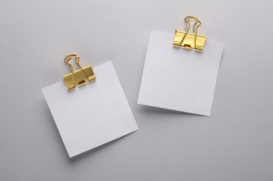 White empty square memo pieces of paper with binders on gray background. Template for design.