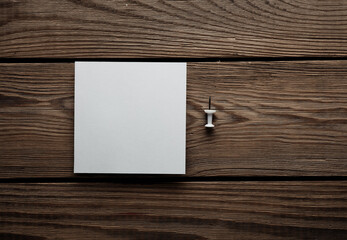 White empty square memo sheet of paper with pushpin on wooden background. Template for design.