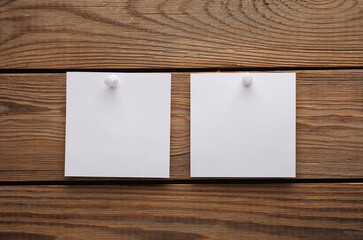 White empty square memo sheets of paper with pushpin on wooden background. Template for design.