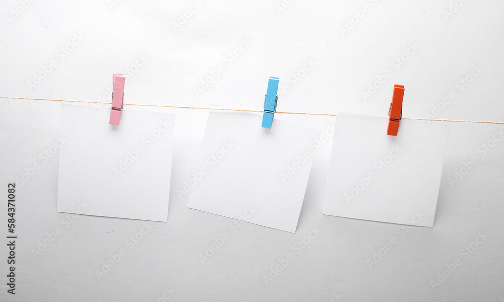 Poster white empty square memo pieces of paper with clothespins on gray background. template for design.