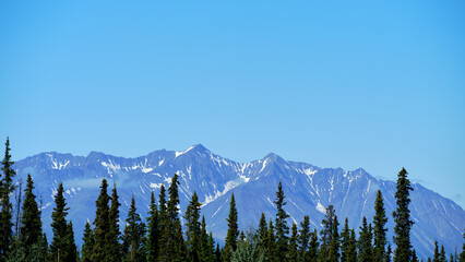 Low lying clouds obscure the snow covered peaks of the mountains along the Alaska Highway in the Yukon