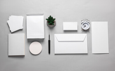 Mockup with white paper office objects. White empty envelope with a letter, lunch bag, business card, notepad and memo papers on a gray background. Template for design