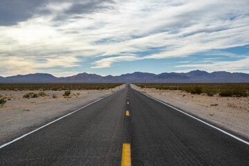Beautiful shot of a highway between dry fields directed to Death Valley