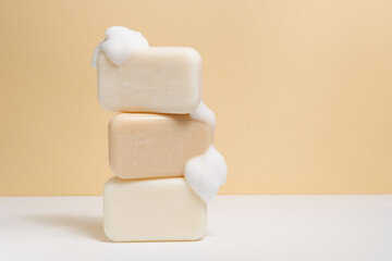 Pieces of natural light soap with foam on a beige background. Place for your design. Concept of...