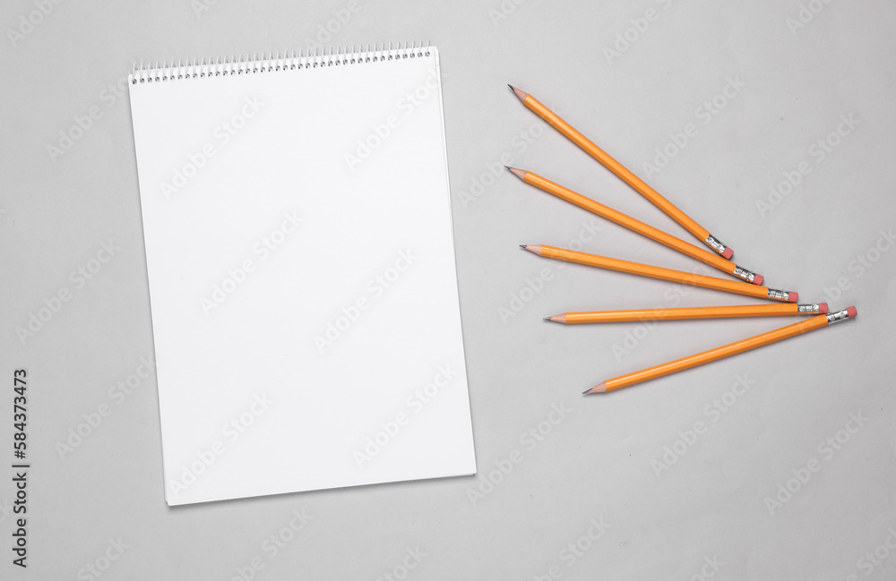 Poster white empty sketchbook for drawing with set of pencils on gray background. top view
