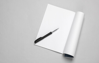 White blank magazine page mockup with pen on gray background