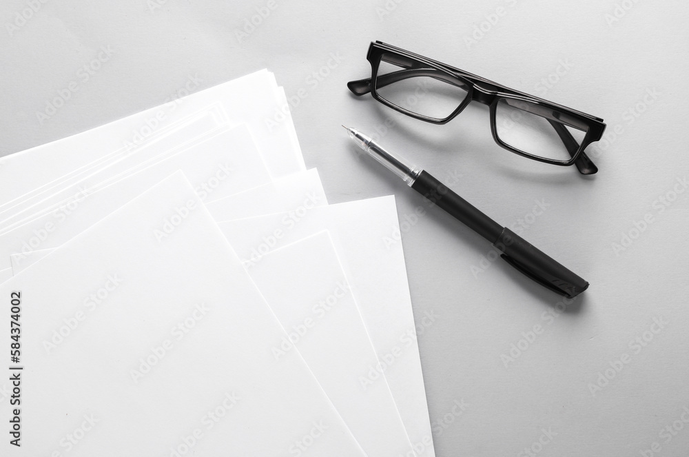 Poster white blank sheets of a4 paper size or documents mockup with pen and eyeglasses on a gray background