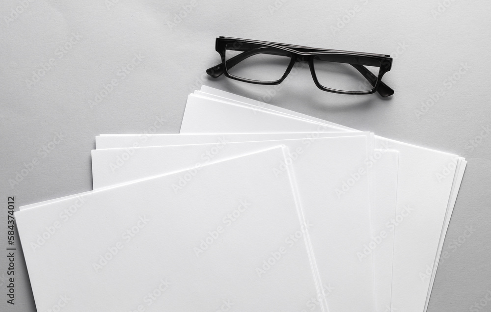 Poster white blank sheets of a4 paper size or documents mockup and eyeglasses on a gray background. templat