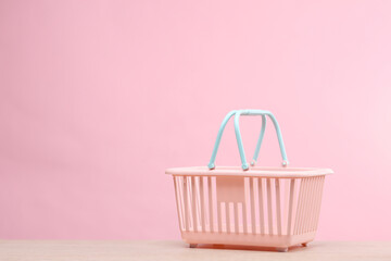 Plastic mini supermarket basket on a pink background. Sale concept