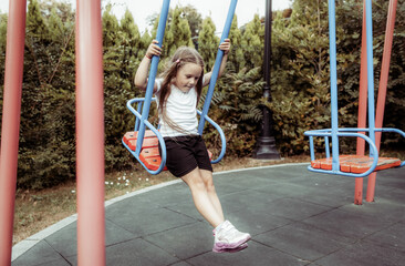 Little cute girl riding a swing outdoors