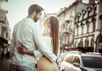 A loving young couple strolls through the city looking at each other embracing. Romantic love concept