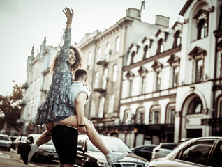 Couple in love. Man carrying girl on his back in the street. Smiling man with beautiful young...