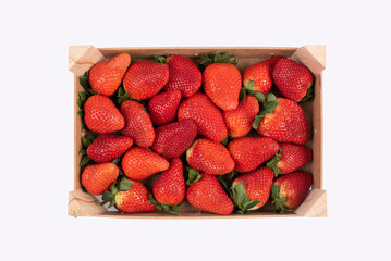 Strawberry harvest in a wooden crate. Red fruits. Top view, isolated on white background.