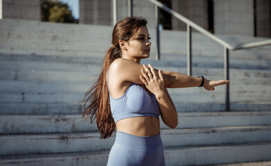 Young fitness woman practicing hand stretching outdoors