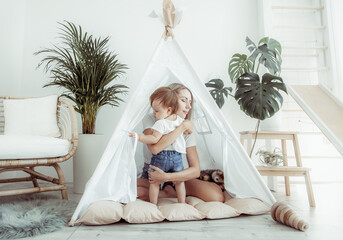 Happy woman mom and her little daughter playing in wigwam at home © splitov27