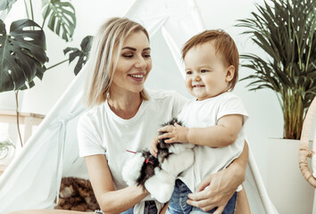 Happy woman mom and her little daughter playing in wigwam at home © splitov27