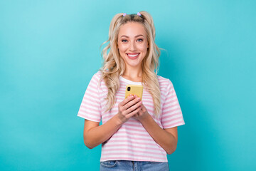 Photo of young smiling curly hair lady wear pink striped t-shirt hold smartphone watching her favorite vlog isolated on aquamarine color background