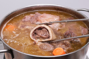 Osseous Tissue and bone broth in soup pot, close-up. Beef boullion. Bones contain collagen which provides the body with amino acids.