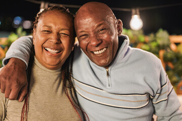 Happy african senior couple smiling on camera during night time outdoor