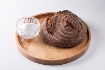 Fresh round black bread with a crispy crust. Close-up on a white background