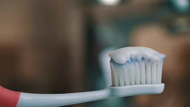 Toothpaste climbs out of the tube onto the toothbrush close-up. Apply toothpaste to the brush. Morning brushing of teeth. Take care of your teeth. Daily hygiene.