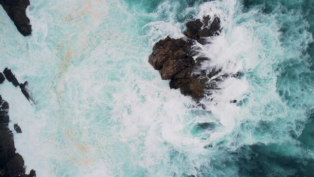 Overhead View Of Foamy Waves Breaking On Outcrops In Caion Beach, Coruna Spain. Aerial Topdown