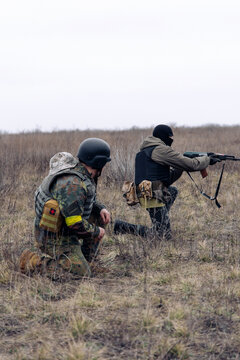 Group of armed Ukrainian soldiers aims in enemy in steppe.