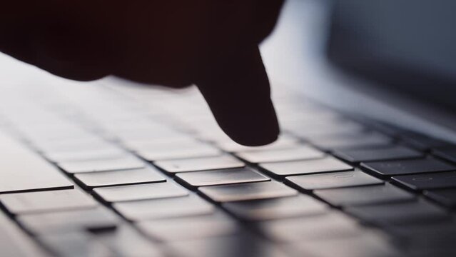 Cropped view of hands typing on laptop keyboard. The man quickly types something with his index fingers on the keyboard.