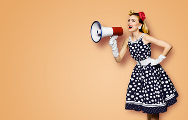 Portrait image of beautiful woman holding mega phone, shout advertising. Pretty girl in black pin up dress, white glows with megaphone loudspeaker. Isolated latte beige background. Big sales ad.