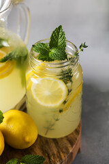 Homemade lemonade with fresh lemon slices and mint leaves in a glass. A summer refreshing drink.