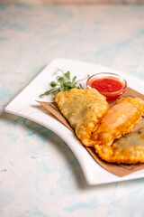fried delicious chebureks with sauce on a white plate