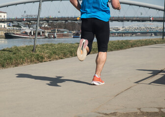 osoba uprawiająca jogging w słoneczny dzień nad rzeką