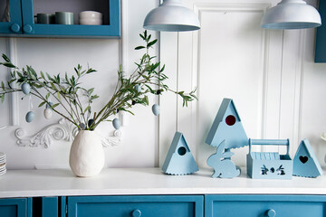 flowers in a vase on the table in the white and blue kitchen with easter decoration