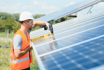 Male engineer in protective helmet installing solar photovoltaic panel system. Alternative energy ecological concept.