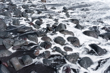 Black Sand Beach with Volcanic Rocks and Foamy Waves