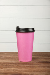 Pink paper coffee cup over white wall