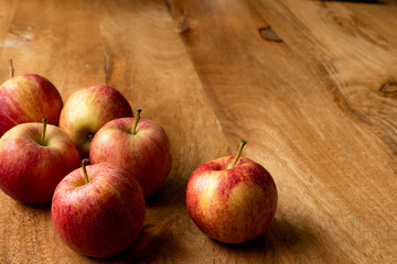 Red apples on a wooden table. A symbol of good health and future happiness associated with Aphrodite, goddess of love. The Christian symbol of sin and forbidden fruit, fertility in Norse mythology.