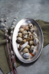 Quail eggs on metal plate with willow branches, Easter decor concept.